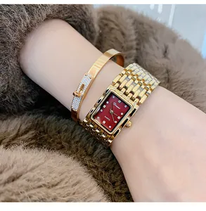 Close-up van Dinimi vierkant gouden horloge en luxe armband op pols met bont achtergrond