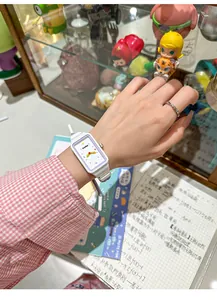 Primer plano de un lindo reloj rectangular con una correa trenzada de colores vivos.