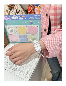 Primer plano de un lindo reloj de pulsera rectangular blanco para estudiantes con agujas de colores