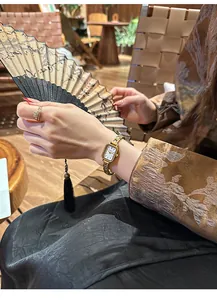 Elegante Vintage-Gold-Quarzuhr in einer Lifestyle-Umgebung mit traditionellem Fächer