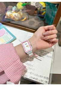 Primer plano de un bonito reloj rectangular blanco con borde rosa en la muñeca de una niña.