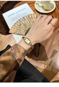 Elegante goldene rechteckige Quarzuhr im Vintage-Stil am Handgelenk in luxuriöser Umgebung