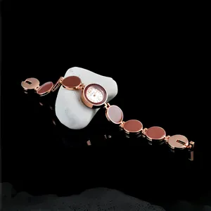 Dettaglio di un orologio a bracciale in oro rosa con maglie circolari marroni su pietra.
