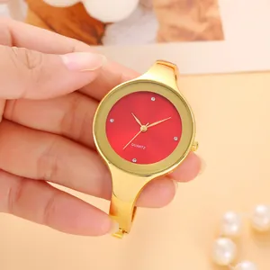 Primo piano di un orologio a bracciale dorato minimalista con elegante quadrante rosso