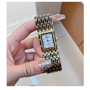 Close-up van een vintage Dinimi dameshorloge, rechthoekig, goud met strass wijzerplaat.