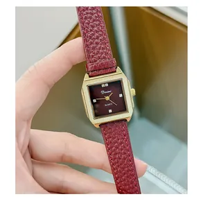 Close-up of retro square women's watch with burgundy leather strap and gold case
