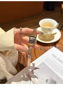 Elegant rose gold rectangular vintage quartz watch held in hand in a cafe setting