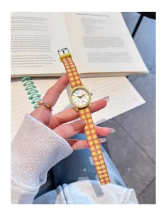 Close-up van een kinderhorloge met geruite siliconen band voor boeken in een hand