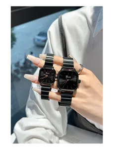 Close-up detail of black minimalist couple watches featuring square dials and metal bands.