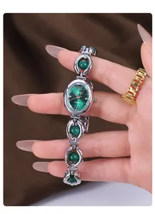 Close-up of a vintage silver bracelet watch featuring an emerald green dial and beads