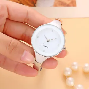 Dettaglio di un orologio a bracciale in argento minimalista con quadrante bianco e cristalli