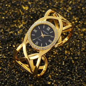 Close-up of a vintage gold bangle watch featuring a rhinestone bezel and crossover strap