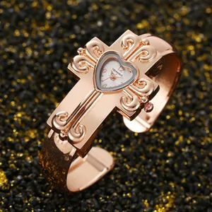 Dettaglio ravvicinato di un orologio vintage in oro rosa con croce e quadrante a cuore