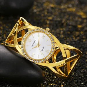 Macro view of gold-plated bangle watch with rhinestone-studded bezel and cross-line design
