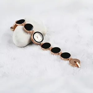 Elegante orologio bracciale oro rosa con maglie nere su sfondo di pelliccia bianca.