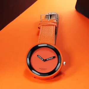 Dettaglio di un orologio al quarzo minimalista con grande quadrante arancione vivace.