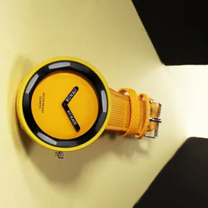 Primo piano di un orologio al quarzo giallo minimalista con quadrante grande e lancette nere.