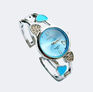 Dettaglio del quadrante azzurro e dei ciondoli a cuore con strass dell'orologio rigido.