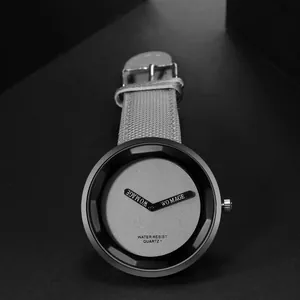 Dettaglio di orologio minimalista con quadrante nero, cinturino grigio e movimento al quarzo