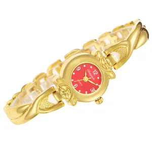 Gros plan d'une montre à quartz dorée pour femme avec motif croisé et cadran rouge vif