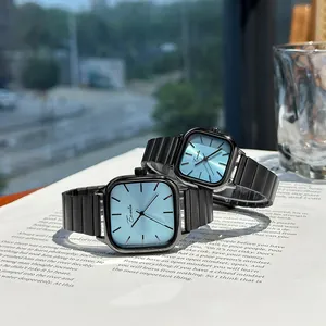 Minimalist couple watches with black square cases and light blue dials on a book.