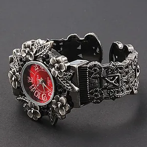Nahaufnahme der Xinhua Vintage-Armreif-Uhr mit Blumenschnitzerei und rotem Zifferblatt.