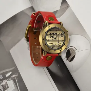 Dettaglio dell'orologio WoMaGe con quadrante a spartito musicale e cinturino in pelle rossa