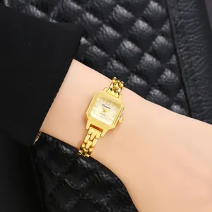 Primo piano dettagliato di un elegante orologio da polso al quarzo quadrato oro su polso