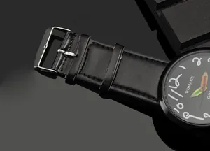 Dettaglio dell'orologio WOMAGE con cinturino in pelle nera e lancette a forma di matita