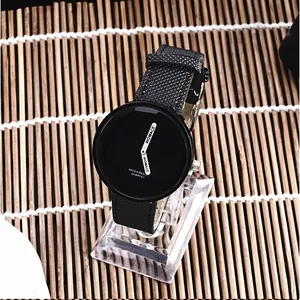 Dettaglio dell'orologio di moda WOMAGE con quadrante nero e cinturino intrecciato