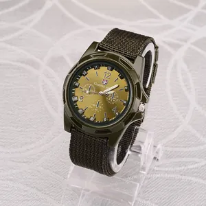 Close-up detail of men's military sports watch with green canvas strap and gold sunray dial