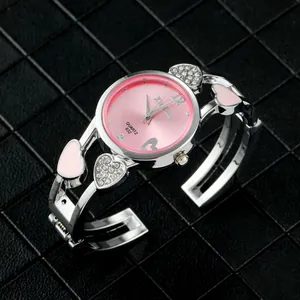 Primo piano di un orologio a bracciale in argento a forma di cuore con quadrante rosa