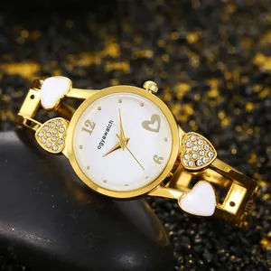 Dettaglio dell'orologio da donna dorato con cuori in smalto bianco e strass brillanti