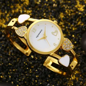 Primo piano orologio da polso dorato donna con eleganti ciondoli a cuore di strass