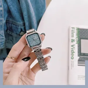 Gros plan détaillé d'une montre carrée minimaliste pour femme avec bracelet en acier et cadran bleu.