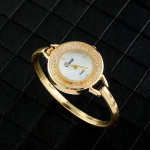 Detalle de primer plano de un reloj de pulsera dorado con bisel de cristales y esfera blanca