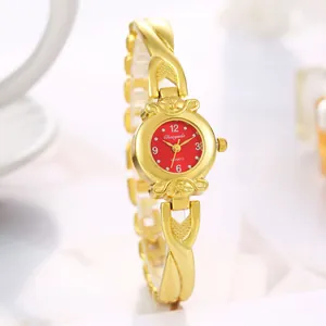Détail d'une montre à quartz dorée pour femme avec bracelet croisé et cadran rouge vif