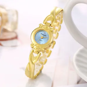 Gros plan d'une montre à quartz dorée pour femme avec bracelet croisé et cadran bleu ciel élégant