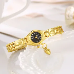 Primo piano di un elegante orologio da polso dorato da donna con ciondolo a cuore e quadrante nero