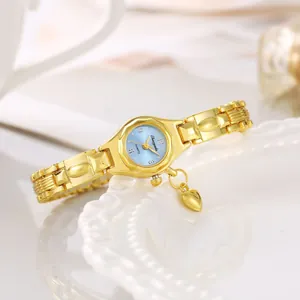 Primo piano di un elegante orologio da donna dorato con un piccolo ciondolo a cuore
