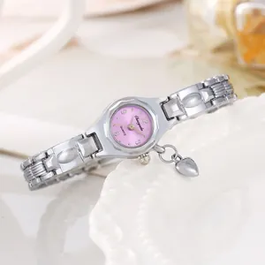 Primo piano dell'orologio da polso argento da donna con ciondolo a cuore e quadrante rosa