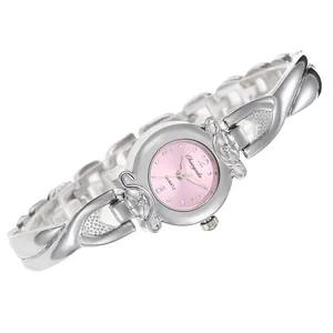 Détail du bracelet croisé argenté et du cadran rose de la montre quartz femme.