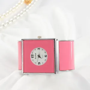 Primo piano di un elegante orologio a bracciale quadrato rosa al quarzo da donna su seta.
