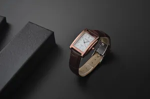 Primo piano dell'orologio quadrato classico WoMaGe da uomo con cinturino in pelle marrone.