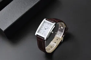 Primo piano dell'orologio quadrato WoMaGe con cinturino in pelle marrone su sfondo scuro