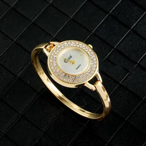 Detalle de reloj brazalete dorado para mujer con bisel adornado con cristales brillantes