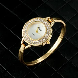 Detalle de reloj brazalete dorado para mujer con bisel de pedrería brillante