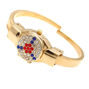 Close-up of elegant gold bangle watch featuring a vibrant rhinestone-encrusted flip cover.