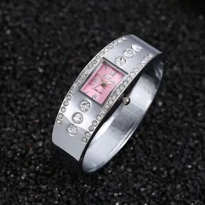 Detalle de un reloj de brazalete plateado con esfera cuadrada rosa y piedras brillantes
