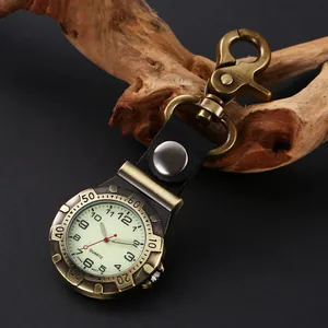 Vintage antique brass quartz clip-on watch with luminous hands on dark background.